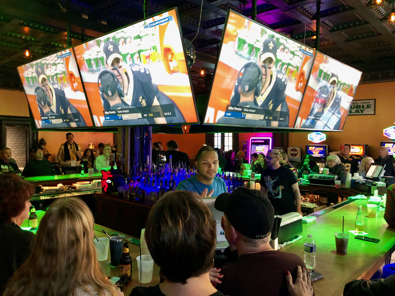 Crowd watching Saints game on multiple TVs